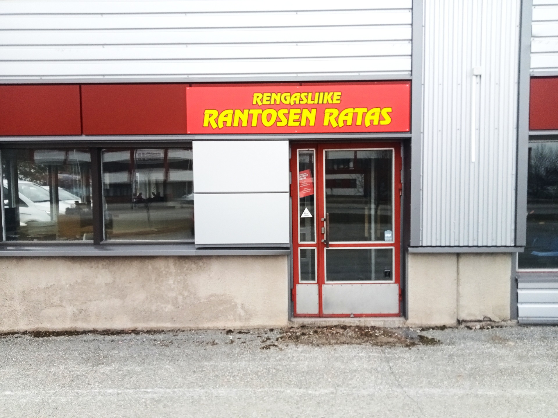 Punainen ovi ja ikkunat teollisuusrakennuksessa, yläpuolella teksti RENGASLIKE RANTOSEN RATAS.
