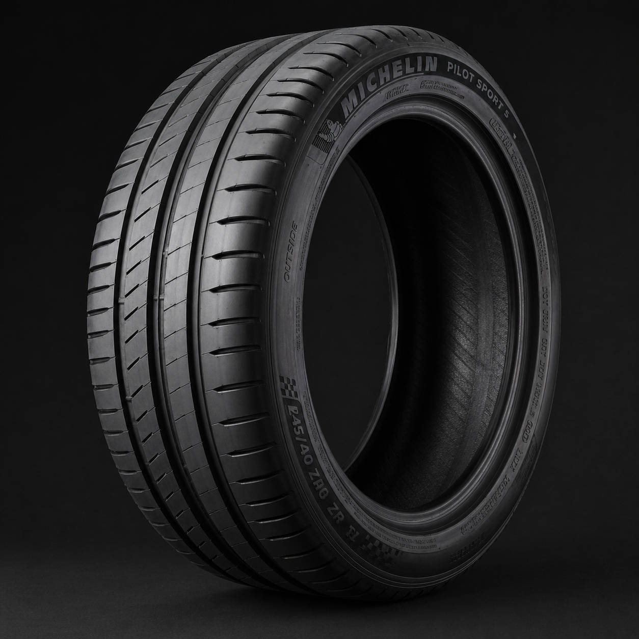 Mustanharmaa rengas lähikuvassa, näkyvät urat ja tekstit Michelin Pilot Sport 5 -renkaan kyljessä.